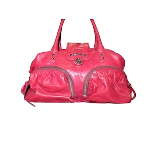 May include: A bright red leather handbag with multiple zippered pockets and a silver lock closure.