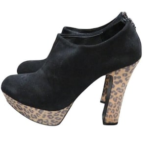 May include: Black suede ankle boots with a platform sole and a high heel. The platform and heel feature a tan and brown leopard print pattern. The boots have a zipper closure at the back.
