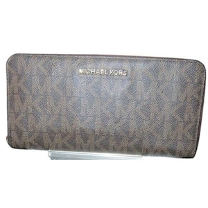 Op de afbeelding: Bruine portemonnee met ritssluiting rondom met een herhalend patroon en de tekst "MICHAEL KORS" in gouden letters. De portemonnee is rechthoekig en lijkt gemaakt van een textuurrijk materiaal.