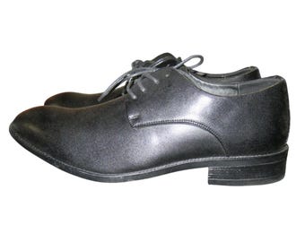 May include: A pair of black leather dress shoes with laces. The shoes have a classic design with a rounded toe and a low heel. The leather has a subtle sheen.