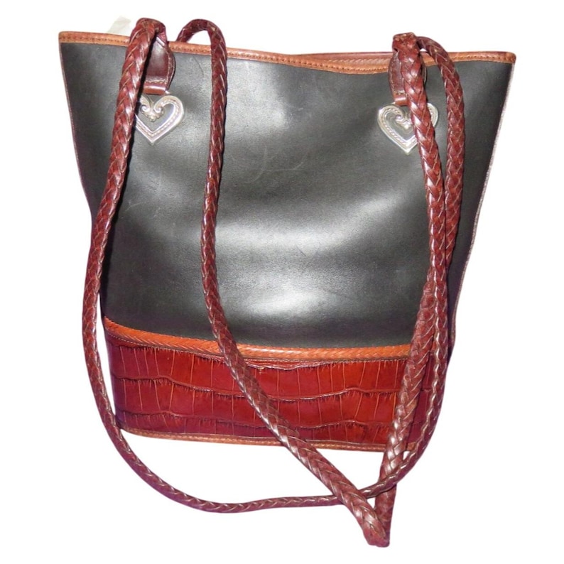 May include: Black leather tote bag with brown braided straps and a brown faux crocodile bottom. The bag has silver heart-shaped charms and a brown trim.