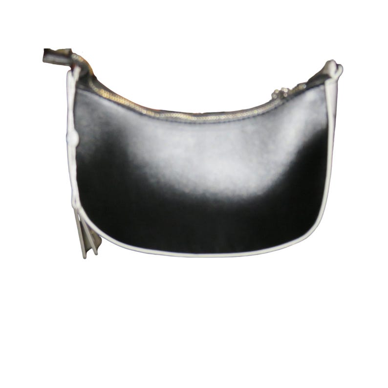 May include: Black crescent-shaped handbag with a white trim and a gold zipper. The bag has a minimalist design and a small tassel detail. The bag is made of a smooth material and is set against a white background.