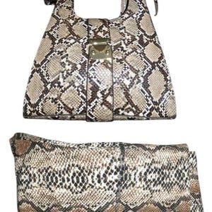 May include: A handbag and a matching clutch bag. The bags feature a snakeskin pattern in shades of brown, tan, and black. The handbag has a top handle and a gold-colored clasp. The clutch is rectangular.