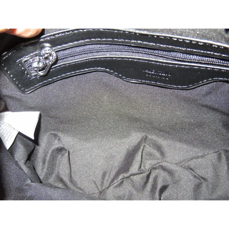 May include: Black handbag interior with a silver zipper and a decorative zipper pull. The interior is lined with black fabric. The brand name "Valentino" is visible on the leather trim. A white tag is visible on the left side.