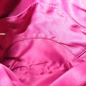 Peut inclure: Int&eacute;rieur d'un sac &agrave; main rose vif. La doublure est en mati&egrave;re lisse, satin&eacute;e, avec une poche visible en haut. L'int&eacute;rieur du sac est d'une couleur rose vif et unie.