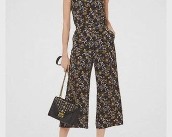 Mono capri negro sin mangas con estampado floral de Michael Kors, talla 0, ancho de pecho 16, largo 48,5.