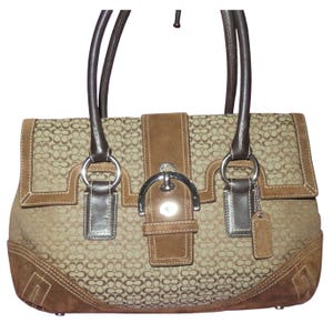 May include: A brown handbag with a repeating pattern. The bag features brown leather handles, trim, and a central flap with a silver buckle. The bag has a suede-like texture on the bottom and flap.