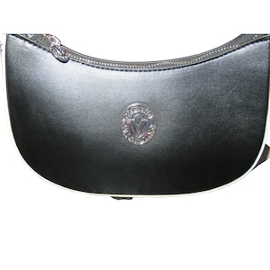 May include: Black crescent-shaped handbag with a silver zipper and a silver emblem. The bag has a white trim along the bottom edge. The emblem is a circular design with the letter "V" in the center.