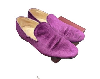Op de afbeelding: Een paar paarse fluwelen loafers. De loafers zijn van het slip-on type en hebben een spitse neus.
