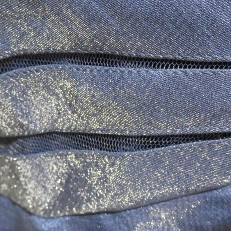May include: Close-up of a navy blue fabric with a shimmering, glittery texture. The fabric is layered with sections of black mesh, creating a textured and layered effect. The overall appearance is elegant and sophisticated.