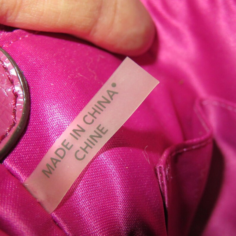 Peut inclure: Gros plan sur un int&eacute;rieur en tissu satin&eacute; rose, possiblement un sac &agrave; main ou une bourse. Une &eacute;tiquette rose clair est visible, avec le texte "MADE IN CHINA" et "CHINE" imprim&eacute; dessus.