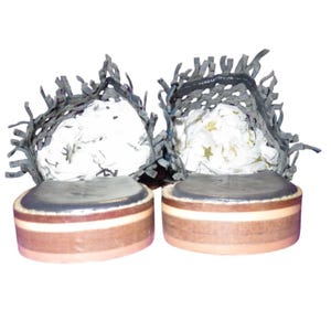 May include: Pair of handmade shoes with a unique design. The soles are brown with a light tan stripe and a dark gray top. The uppers are dark gray with a fringed, woven design. The insides are filled with white paper.