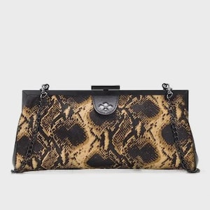 May include: A rectangular clutch bag with a snakeskin pattern in brown and tan. It features a black frame, clasp closure, and a chain strap. This stylish bag measures approximately 28 cm in length.