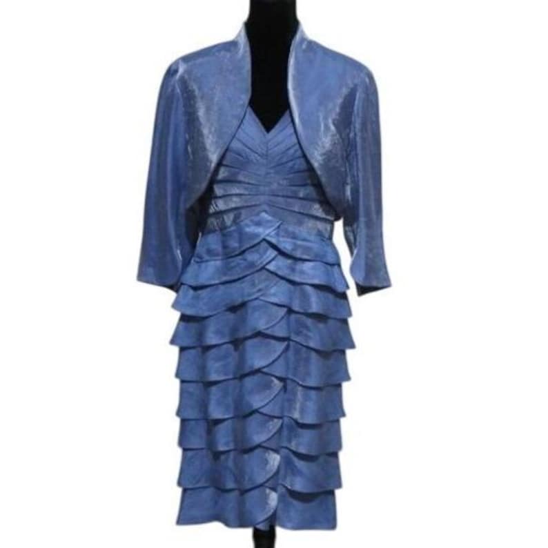 May include: A formal blue dress and matching bolero jacket. The dress features a V-neck and a tiered skirt. The bolero has three-quarter sleeves. The outfit is displayed on a black mannequin.