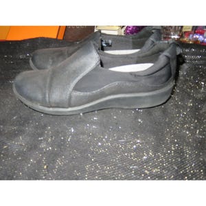 May include: A pair of black slip-on shoes with a black elastic panel and a white insole.