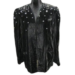 May include: Black velvet jacket with a V-neck and long sleeves. The jacket is adorned with scattered, sparkling rhinestones on the shoulders and upper chest. It has a classic, tailored design with a front closure and pockets.