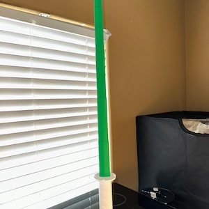 Könnte beinhalten: Ein grünes und weißes Spielzeugschwert. Die Klinge ist leuchtend grün, und der Griff ist weiß mit einem strukturierten Griff. Das Schwert besteht aus Kunststoff und scheint ein Kinderspielzeug oder ein Dekorationsgegenstand zu sein. Das Schwert ist etwa 80 cm lang.