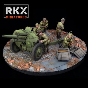Könnte beinhalten: Miniatur-Diorama mit einer grünen Artilleriekanone und Soldaten in Uniformen. Die Szene spielt auf einer kreisförmigen Basis mit Ziegel- und Steindetails. Das Logo "RKX MINIATURES" befindet sich oben links.