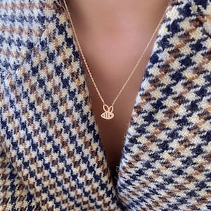 May include: A gold chain necklace with a delicate bee pendant. The bee is outlined in gold and has a small, detailed design.