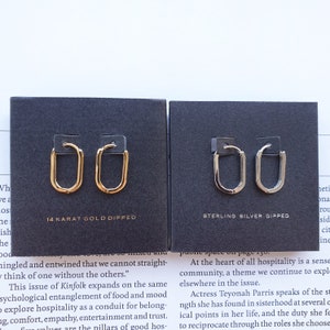 May include: Two pairs of hoop earrings, one pair is gold and the other is silver. The earrings are displayed on black cards with the text "14 Karat Gold Dipped" and "Sterling Silver Dipped".