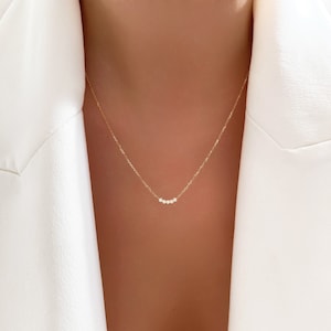 May include: A delicate gold chain necklace with a row of small, clear stones.