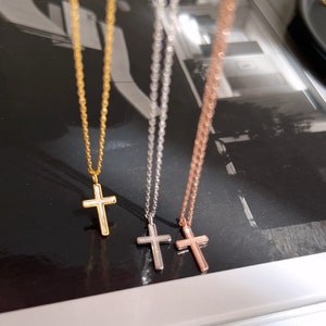 May include: Three gold, silver, and rose gold necklaces with a cross pendant. The cross pendants are white with a gold outline.