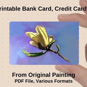 May include: A printable bank card skin featuring a floral design. The card displays a yellow flower with green leaves against a blue and purple background. The text "Printable Bank Card, Credit Card Skin" is at the top.