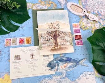 Può includere: Un set di partecipazioni di nozze con un'illustrazione ad acquerello di un albero con luci colorate, un nastro bianco e un cartoncino con l'itinerario stampato. Il cartoncino elenca gli eventi per venerdì 17 e sabato 18 aprile 2026, accanto a un ornamento blu a forma di pesce.