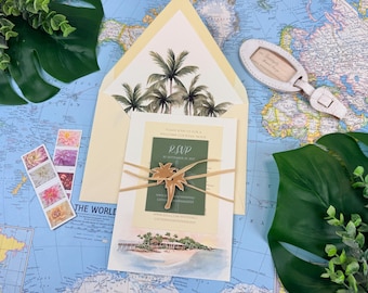 Può includere: Un set di partecipazioni di nozze con busta color crema illustrata con palme, una carta centrale con inserto RSVP verde, un ciondolo a forma di palma in legno legato con spago, un'etichetta per bagagli e francobolli floreali su una mappa.