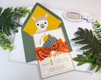 Può includere: Un biglietto d'invito con grafica di montagna, nastro arancione paisley e il testo Meet Us At Camp Alpaca, Troop #1, June 7, 2025, 4:00-7:30 PM, Bluebird Alpaca Farm, 44 Willow Ave, Peapack NJ, in una busta verde con illustrazione di alpaca.