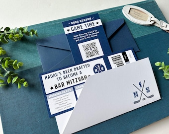 May include: A navy blue and white Bar Mitzvah invitation designed as a sports ticket. The ticket features the text 'Nadav's been drafted to become a Bar Mitzvah', a QR code, and a hockey-themed logo with crossed sticks and a lightning bolt.