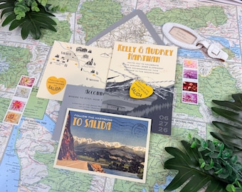 Può includere: Un set di partecipazioni di nozze con una mappa di Salida, una cartolina con paesaggio montano e un biglietto intitolato Kelly & Audrey Hartman. Il set include un'etichetta gialla a forma di cuore e francobolli con motivi floreali.
