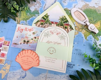 Può includere: Un set di partecipazioni di nozze con una busta verde pallido con un'illustrazione ad acquerello di un resort, un cartoncino con il nome Layla Wright, un cartoncino RSVP a forma di conchiglia e un'etichetta per bagagli.