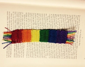 May include: A rainbow-colored crocheted bookmark with a fringe. The bookmark is placed on a page of a book with text about the "Finding of the Ring".