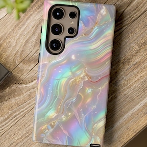 以下が含まれることがあります： 虹色のマーブル模様のスマートフォンケース。ケースは、ピンク、紫、緑の色合いの金色の静脈パターンが特徴です。携帯電話ケースには、複数のレンズを備えたカメラアレイがあります。