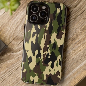 May include: A smartphone case with a camouflage pattern in shades of green, brown, and black. The case is on a wooden surface. The phone case has a camera with three lenses.