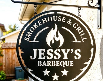 May include: Black metal sign for "Jessy's Barbeque" with the words "Smokehouse & Grill" in a circular design. The sign features a flame graphic and three stars. It is suspended by a decorative black metal bracket.
