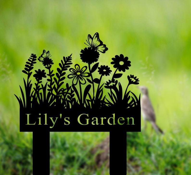 Puede incluir: Se&ntilde;al de jard&iacute;n de metal negro con una silueta de flores, mariposas y hierba. La se&ntilde;al dice "Lily's Garden".