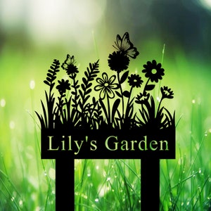 Könnte beinhalten: Schwarzer Gartenpfahl aus Metall mit einer Silhouette von Blumen, Schmetterlingen und Gras. Der Pfahl hat ein Schild mit der Aufschrift "Lily's Garden".