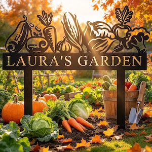 May include: A black metal garden sign featuring a cutout design of various vegetables including carrots, corn, and squash, with the text LAURA'S GARDEN in capital letters. The sign is supported by two vertical posts and stands in a garden.