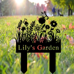 Puede incluir: Letrero de jard&iacute;n de metal negro con una silueta de flores, mariposas y hierba. El letrero dice "Lily's Garden".