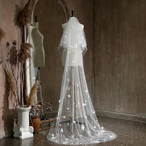 May include: A white bridal veil with delicate floral embroidery. The veil is made of soft tulle and has a long, flowing design.