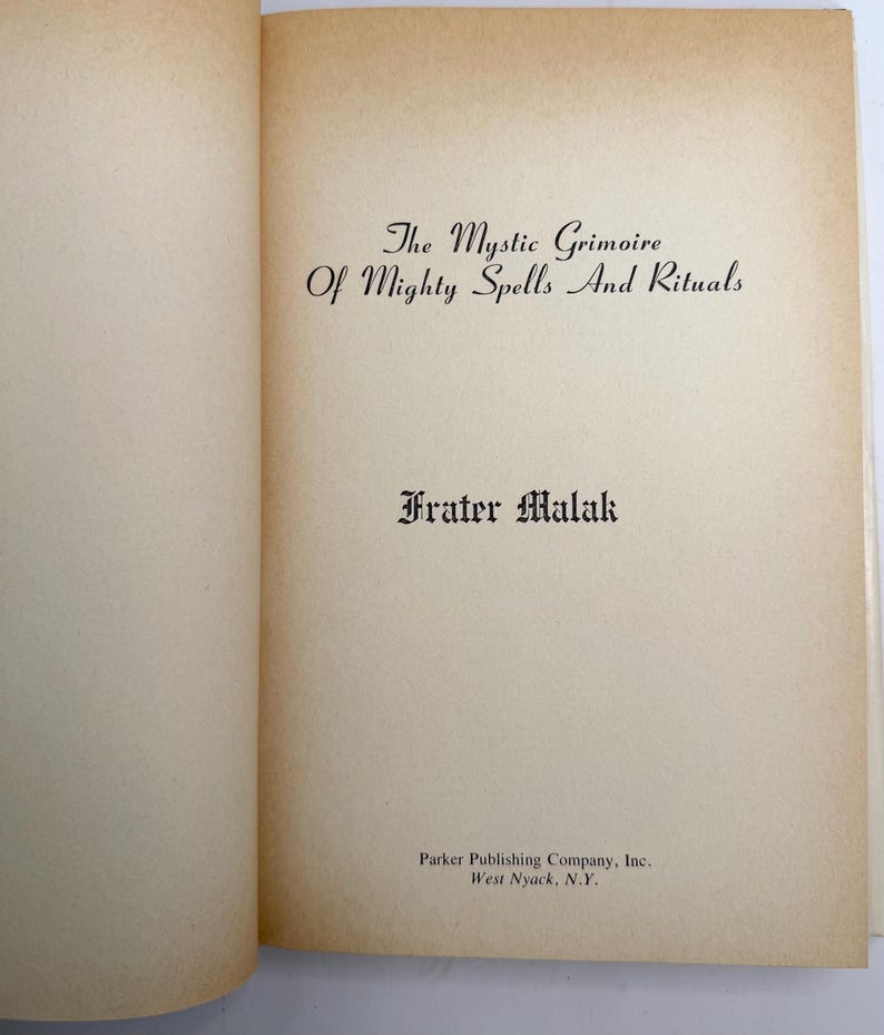 May include: Open book with text: "The Mystic Grimoire Of Mighty Spells And Rituals" by Frater Malak. The book's pages are off-white with a slightly aged appearance. The publisher is Parker Publishing Company, Inc., West Nyack, N.Y.