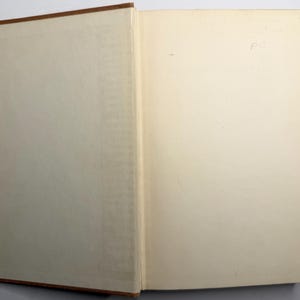 May include: An open book with a brown cover and off-white pages. The binding is visible, and the pages are slightly yellowed with age. Handwritten text is visible on the right page.