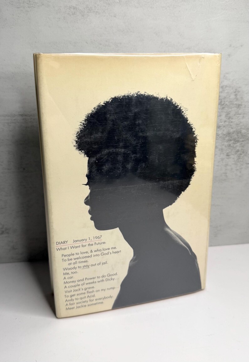 May include: A book cover with a black silhouette of a person with an afro. The cover is a light beige colour with text that includes "DIARY January 1, 1967" and a list of aspirations.