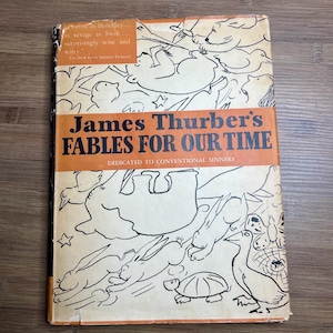 May include: Vintage book cover for "James Thurber's Fables For Our Time." The cover features a cream background with black line drawings of animals and stars. The title is in large orange letters, with a quote from The New York Herald Tribune.