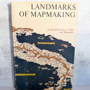 May include: A hardcover book titled Landmarks of Mapmaking: An Illustrated Survey of Maps and Mapmakers. The cream-colored cover features a vintage-style map of the Adriatic Sea region with dark blue water, tan landmasses, and black text.
