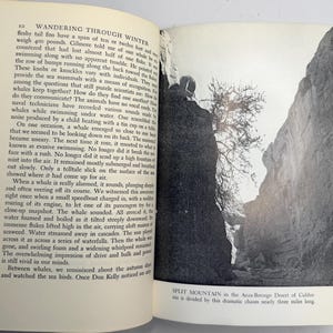 May include: A black and white photograph of a book open to a page with text and a landscape image. The landscape shows a narrow canyon with tall rock walls. The text describes whales and the ocean.