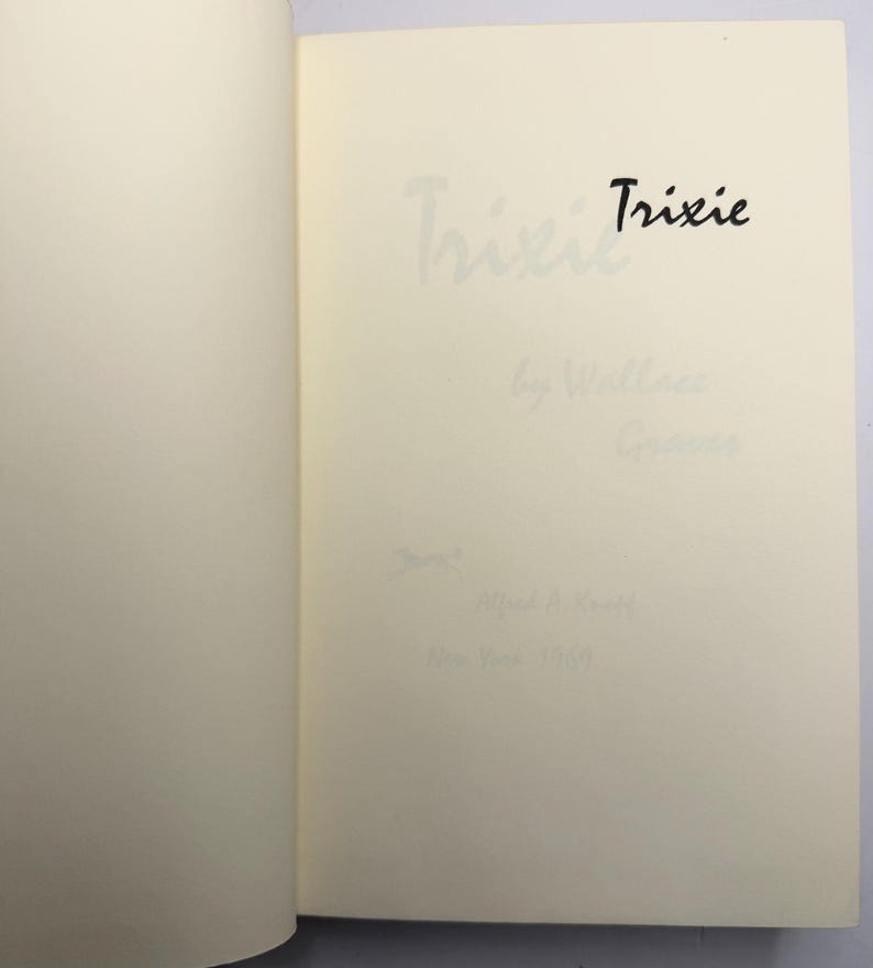 May include: Open book pages with the title "Trixie" in black ink. The author's name and publisher's information are also visible in light grey ink. The book's pages are a cream colour.