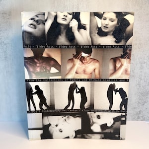 May include: A hardcover book titled Video Acts from the Collections of Pamela and Richard Kramlich and P.S.1 Contemporary Art Center. The cover features a grid of black and white photographic stills showing various human figures and silhouettes.